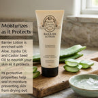 A tube of Skin Saver Labs Barrier Lotion stands on a wooden cutting board with a bowl of aloe vera gel and sliced aloe leaves around it. Text on the left reads 'Moisturizes as it Protects' and describes the ingredients include aloe, jojoba, and castor seed oil.
