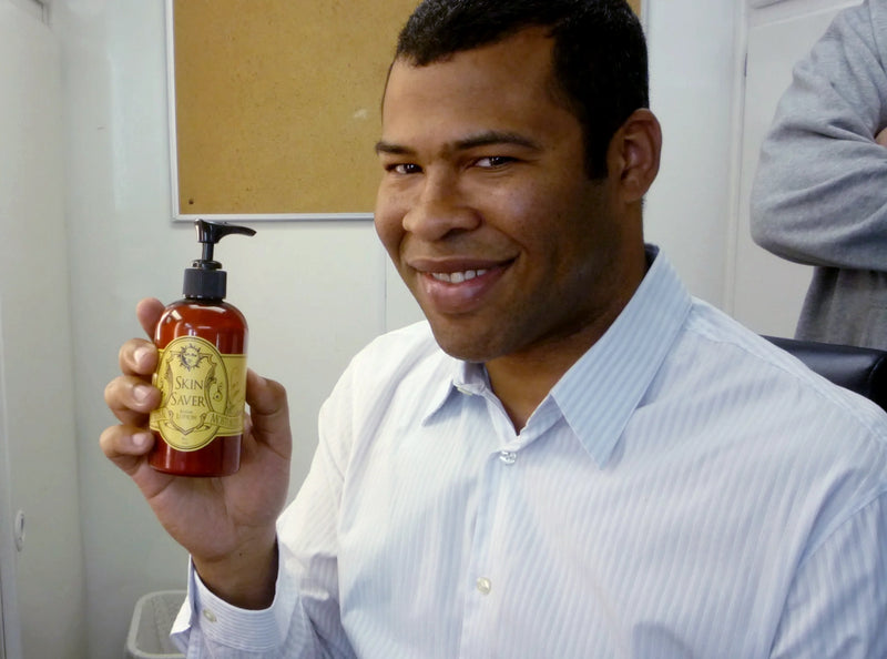 Jordan Peele holding a bottle of Skin Saver Barrier Lotion